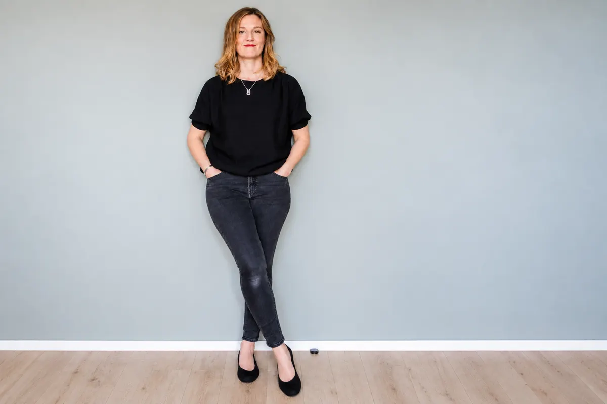Bettina Pöhler steht lächelnd vor einer hellen Wand